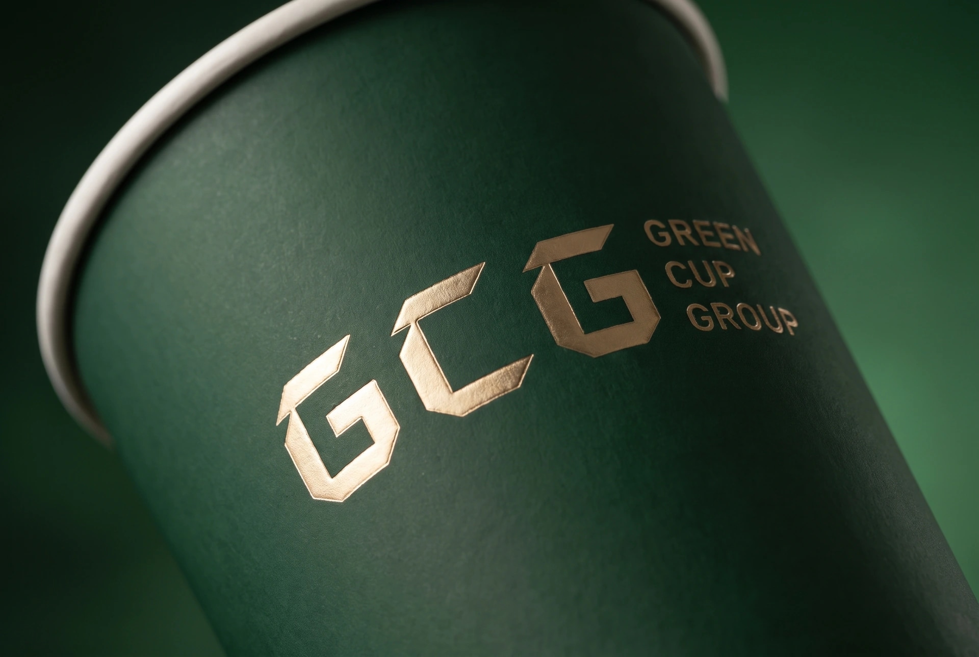 Finish illustration: close-up of raised gold foil GCG lettering on a curved deep-green paper cup.